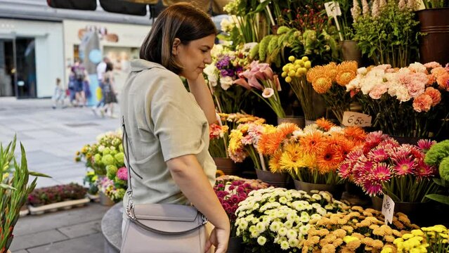Young beautiful hispanic woman touching colourful flowers in the streets of Vienna