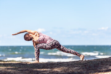 Young caucasian woman practicing yoga at seashore - 671874732
