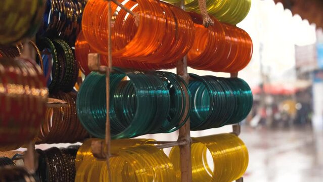 A set of colorful, handmade, traditional Indian glass bangles hanging in the shop. Rainy Day. Shallow depth of field.  