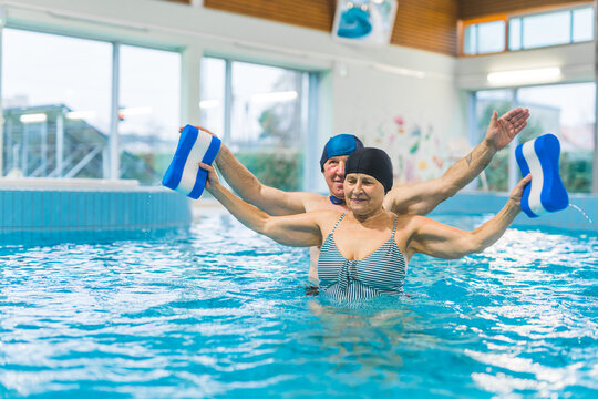 Cheerful adult happy senior couple having fun in an indoor swimming pool doing exercise. High quality photo