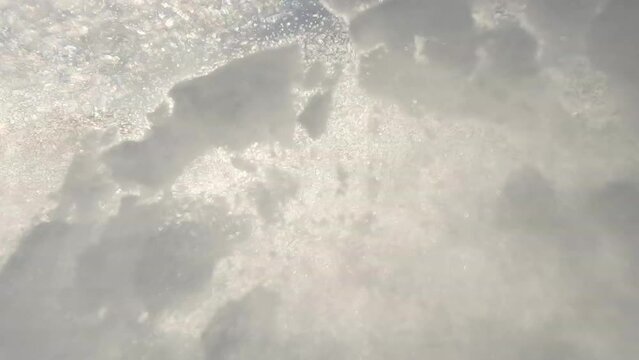 LENS FLARE, SLOW MOTION Recreational skier sprays snow while skiing on ski track. Experienced female skier is carving on slopes of ski resort in snowy Austrian Alps. Nice sunny day for winter sports.