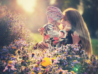Happy mother and daughter in garden among blooming flowers