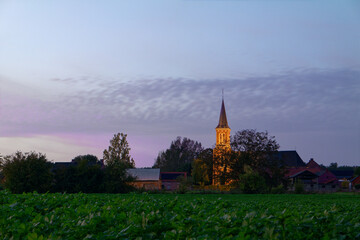 Oświetlony kościół w Belgii, krajobraz na wsi. - obrazy, fototapety, plakaty