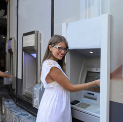 Young happy brunette woman withdrawing money from credit card