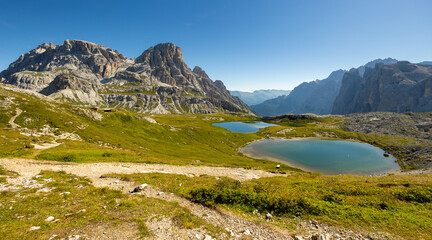 Naklejka na ściany i meble Spectacular scene of small serene natural lakes Bodenseen under summer sun surrounded by greenery and rocky mountains in Sexten Dolomites in South Tyrol, Italy