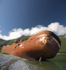 Shipwreck site in small bay, Old rusty whaling ship on the sea shore, Kamchatka, stern view, Morzhovaya bay