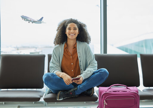 Airport, black woman and portrait of a young person at flight terminal waiting for airplane travel. Passport document, smile and sitting solo female traveler feeling happy with freedom from adventure
