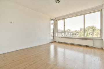 an empty living room with wood flooring and large windows looking out onto the street in front of the house