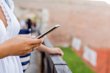 Happy young woman texting sms outdoors.