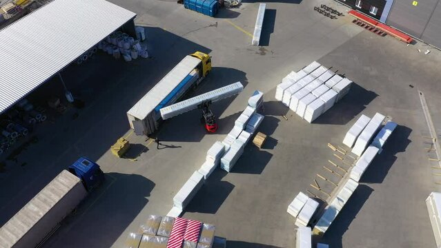 Aerial view of a semi trucks with cargo trailers standing on warehouses ramps for loading/unloading goods on the big logistics park with loading hub