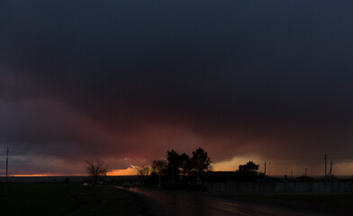 Landscape at sunset. A thunderstorm is approaching the village. Tragic gloomy sky. Panorama.