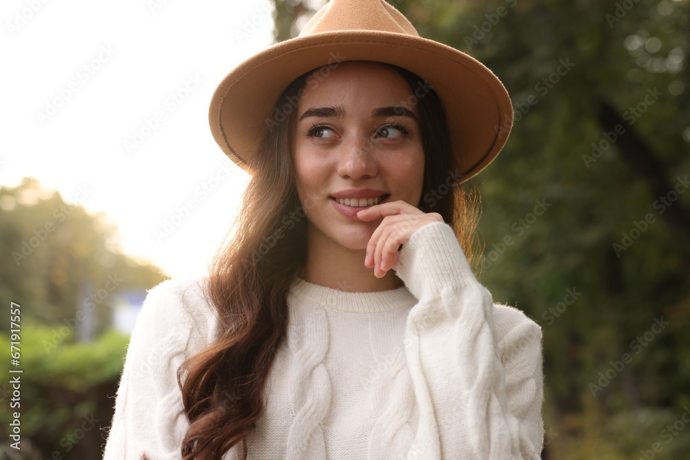 Sticker Beautiful young woman in stylish warm sweater and hat outdoors