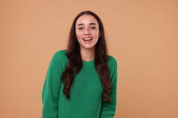 Fototapeta premium Beautiful young woman in stylish warm sweater on beige background