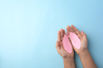 Child holding paper human lungs on light blue background, top view. Space for text - Powered by Adobe