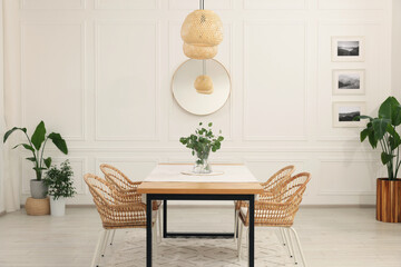 Stylish dining room with cozy furniture, mirror and plants