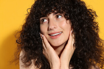 Beautiful young woman in sunlight on orange background