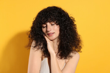 Beautiful young woman in sunlight on orange background