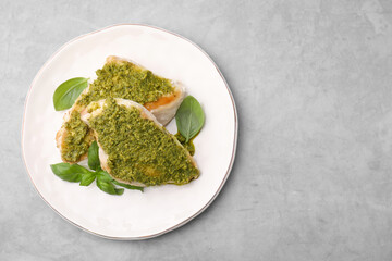 Delicious chicken breasts with pesto sauce and basil on light gray table, top view. Space for text