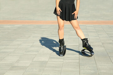 Fototapeta premium Woman in kangoo jumping boots outdoors on sunny day, closeup. Space for text