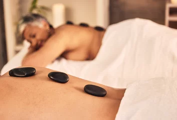 Vitrage gordijnen Massagesalon Closeup, spa and stone massage on back of people for skincare cosmetics, holistic therapy and muscle healing at beauty salon. Relax, wellness resort and self care of hot rocks for zen, peace or detox