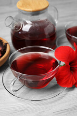 Delicious hibiscus tea and beautiful flower on light wooden table
