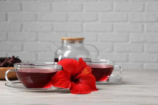 Delicious hibiscus tea and beautiful flower on light wooden table, space for text