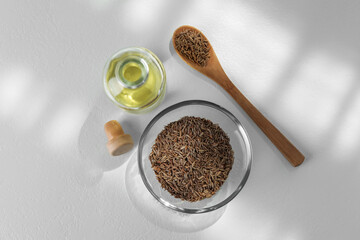 Caraway (Persian cumin) seeds and essential oil on white table, flat lay