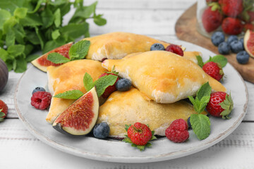 Delicious samosas with figs and berries on white wooden table, closeup