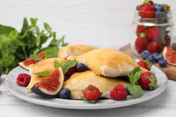 Delicious samosas with figs and berries on white wooden table, closeup