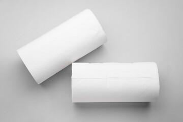 Rolls of tissue towels on light grey background, flat lay