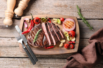 Delicious fried beef meat served with vegetables on wooden table, flat lay
