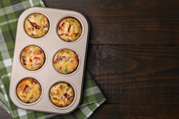Freshly baked bacon and egg muffins with cheese in tin on wooden table, top view. Space for text
