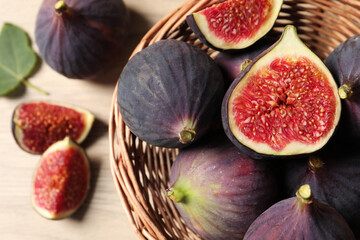 Whole and cut ripe figs on wooden table, top view