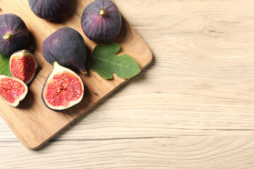 Whole and cut ripe figs on wooden table, top view. Space for text