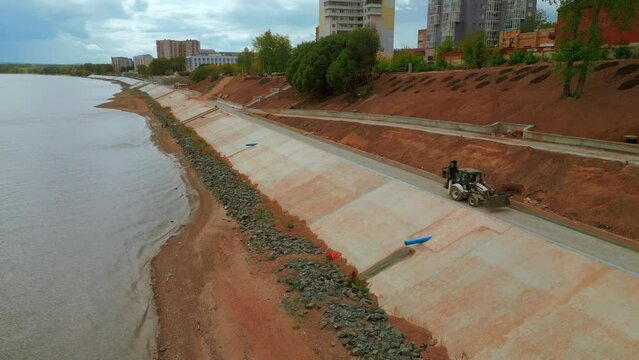 Construction and strengthening of a new safety embankment along the river. Clip. Aerial view ov the improving city area.