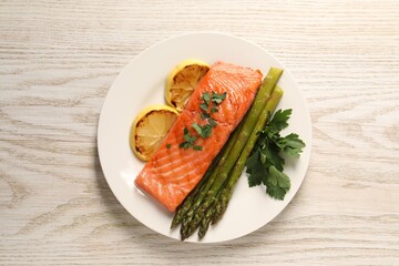 Tasty grilled salmon with asparagus and lemon on white wooden table, top view