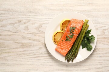 Tasty grilled salmon with asparagus and lemon on white wooden table, top view. Space for text