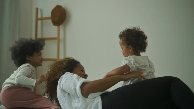 Happy African American mother playing with his girl in bedroom at home