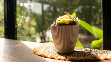 Yellow flowers in a white vase, Placed next to the window There was soft sunlight shining.