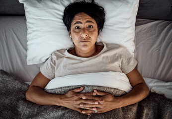 Insomnia, portrait and senior woman in bed from above with menopause, anxiety or stress in her...