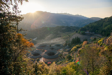 Tianluokeng Tulou cluster behind the trees during the sunset in the village
