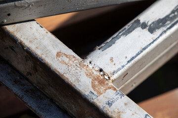 Old rusty metal ladder with cracked paint. Shallow depth of field.
