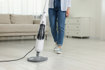 Fototapeta premium Woman cleaning floor with steam mop at home, closeup