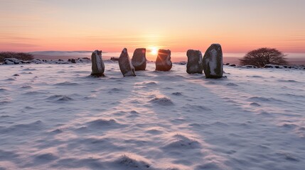 A tranquil winter scene showcases standing stones amidst a snow-covered landscape at sunset. The sky is painted in hues of pink and orange, casting a soft glow over the frosty terrain.