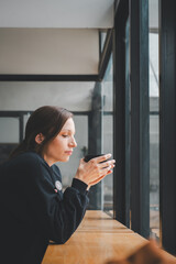 Fototapeta premium Portrait of young woman drinking coffee at table in cafe