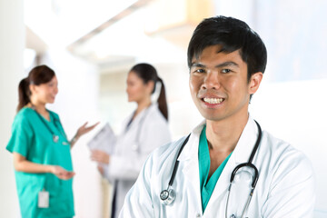 Fototapeta premium Portrait of a Young male Doctor with team in background.