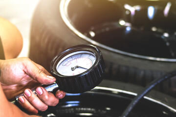 Mechanic using a pressure gauge to measure the pressure of the car. - obrazy, fototapety, plakaty