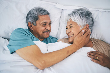 Obraz premium Bed, love and happy senior couple in a bedroom bonding as care, support and relax to enjoy retirement in a home. Smile, solidarity and elderly people, man and woman with trust in marriage together