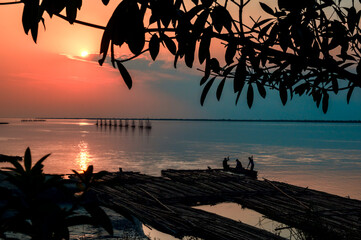 Sunset over the River.  Silhouette of a tree and Fishermen at Brahmaputra River. Dibrugarh, Assam, India.