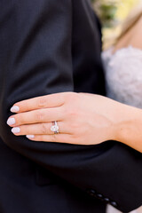 Bride in dress rests hand on husbands arm closed fingers displaying wedding ring